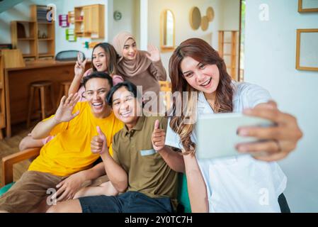 A group of Indonesian people are smiling and taking a picture of themselves with a cell phone. Scene is happy and friendly Stock Photo