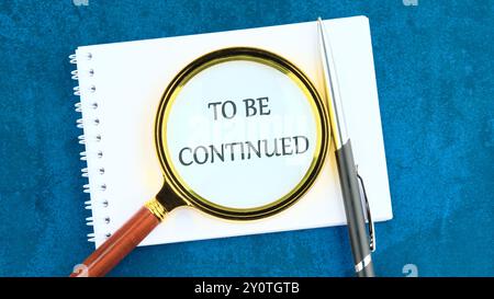 TO BE CONTINUED text written through a magnifying glass on a blank sheet of notepad Stock Photo