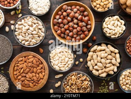 Peanut,hazelnut,walnut,almonds,pistachio,sunflower,pumpkin,chia,pecan and cashew mixed healthy nuts and seeds in various bowls on dark kitchen table. Stock Photo