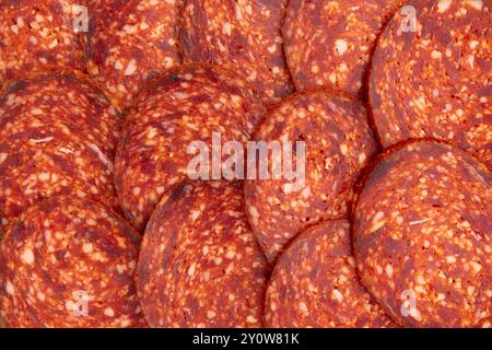 smoked sausage salami with paprika cut into pieces as background, traditional spanish sausage pepperoni, top view, flat lay Stock Photo
