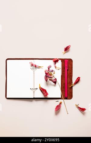 Open notebook with dried flower petals and pen. Creativity, writing or nostalgia concepts. Stock Photo