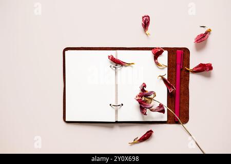 Open notebook with dried flower petals and pen. Creativity, writing or nostalgia concepts. Stock Photo