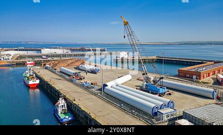 Scrabster Harbour Caithness Scotland the harbour quays with fishing boats wind turbines and stacked timber Stock Photo