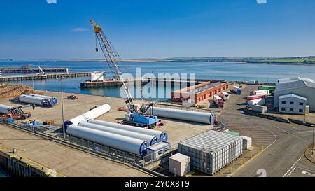 Scrabster Harbour Caithness Scotland the harbour with wind turbines and stacked timber in late summer Stock Photo