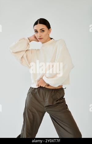 A fashionable young woman showcases her stylish autumn ensemble, exuding elegance in a modern studio environment. Stock Photo