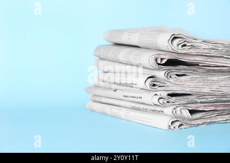 Stack of newspapers on light blue background, space for text Stock Photo