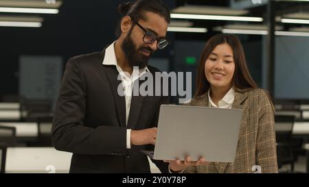 Diverse multiracial colleagues business people in office discussing new online laptop startup project Indian Arabian businessman mentor consult talk Stock Photo