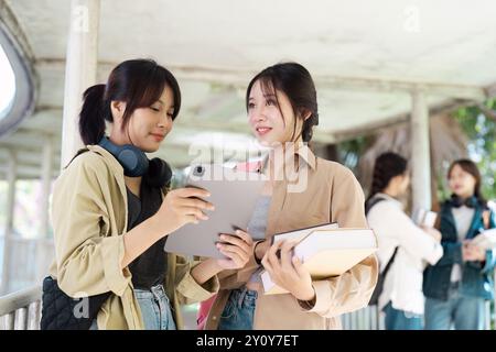 University Students Studying Together Outdoors with Books and Tablet, Engaged in Collaborative Learning Stock Photo