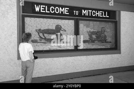 Caucasian female tourist looking at the 'Welcome to Mitchell' sign at the Corn Palace Convention & Visitors Bureau in Mitchell, South Dakota. USA Stock Photo