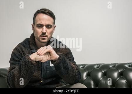 Portrait of man sitting on sofa thinking Stock Photo