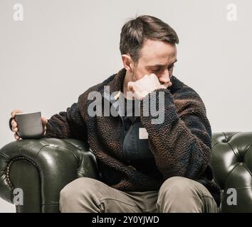 Man of sofa with cup of tea thinking Stock Photo