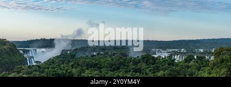 Iguazu National Park at sunrise with a plume of mist rising from the Devil's Throat.  The complex of falls extends for 2.7 kilometers with the  border Stock Photo