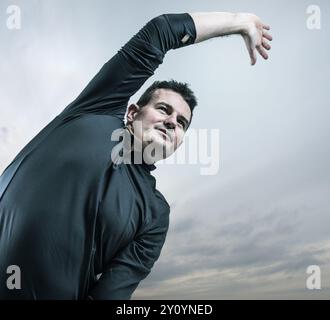 Portrait of man doing stretching exercises outside Stock Photo
