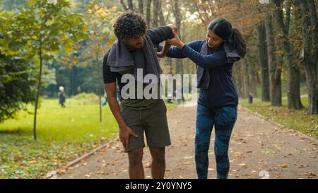 Outdoors in nature park Indian Arabian couple friends man woman stop after cardio fast run jog running man tired exhausted resting feel bad unwell Stock Photo