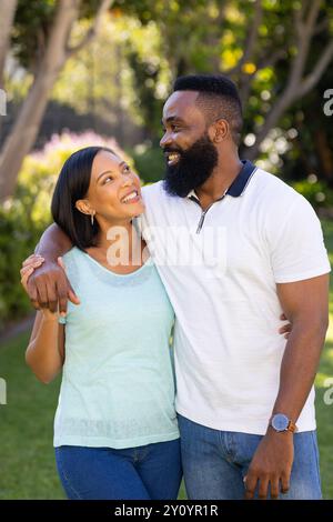 Smiling couple embracing and looking at each other in sunny garden Stock Photo