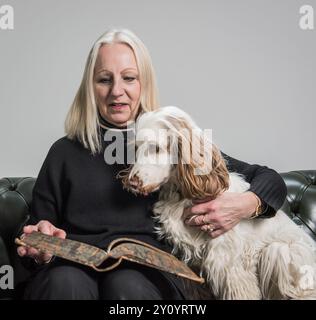 senior woman reading with spaniel dog on lap Stock Photo