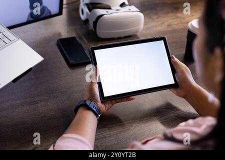 Holding tablet with blank screen, person working in tech office with VR headset, copy space Stock Photo