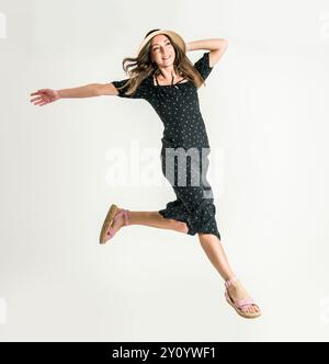 Young woman jumping in studio wearing hat Stock Photo