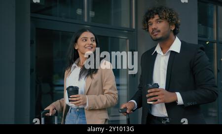 Talking business coworkers colleagues in city smiling Arabian man businessman Indian woman businesswoman arrive in city airport station with luggage Stock Photo