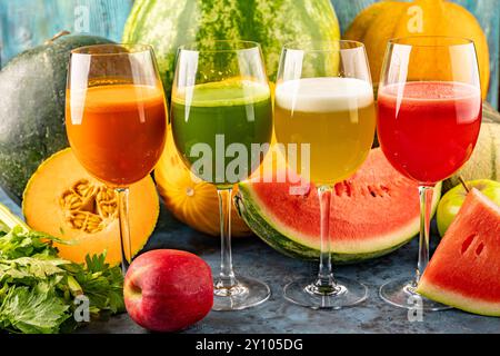 Watermelon and melon fresh drink juice in the glasses. The drink is on a blue background with a half watermelon melon, celery and apple in the backgro Stock Photo