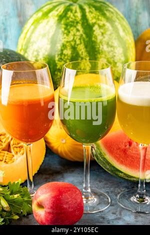 Watermelon and melon fresh drink juice in the glasses. The drink is on a blue background with a half watermelon melon, celery and apple in the backgro Stock Photo
