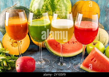 Watermelon and melon fresh drink juice in the glasses. The drink is on a blue background with a half watermelon melon, celery and apple in the backgro Stock Photo