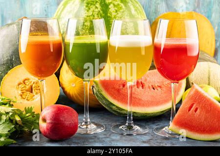 Watermelon and melon fresh drink juice in the glasses. The drink is on a blue background with a half watermelon melon, celery and apple in the backgro Stock Photo