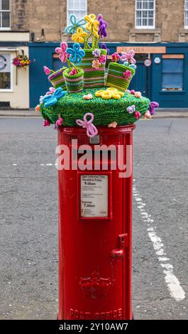 Knitted topper of colourful flowerpots on Royal Mail red postbox, Haddington High Street, Scotland, UK Stock Photo