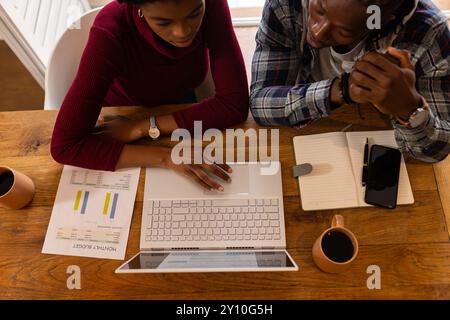 Analyzing financial documents, African American couple working with laptop and notepad at home Stock Photo