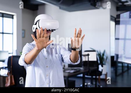 Using vr headset,  woman interacting with virtual environment in office setting, copy space Stock Photo