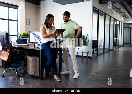 Collaborating in modern office, colleagues using tablet discussing project and smiling Stock Photo