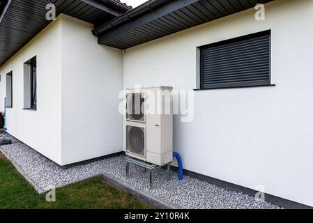 Two efficient outdoor heat pump units placed in front of the house. Stock Photo