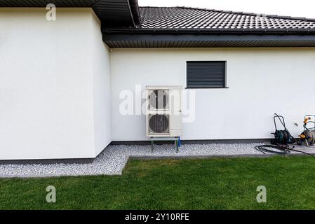 Two efficient outdoor heat pump units placed in front of the house. Stock Photo