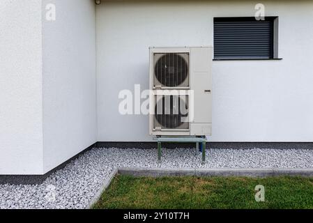 Two efficient outdoor heat pump units placed in front of the house. Stock Photo