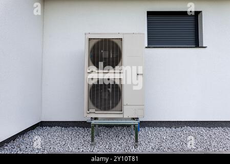 Two efficient outdoor heat pump units placed in front of the house. Stock Photo