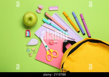 Backpack, different school stationery and apple on light green background, flat lay Stock Photo