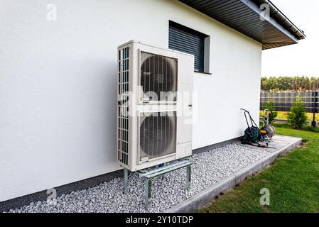 Two efficient outdoor heat pump units placed in front of the house. Stock Photo
