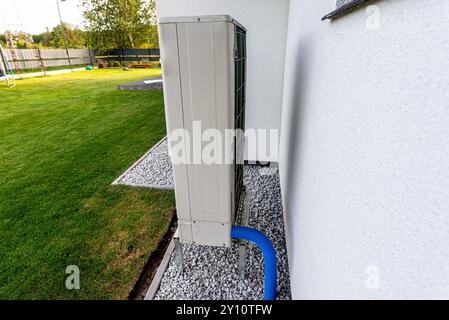 Two efficient outdoor heat pump units placed in front of the house. Stock Photo