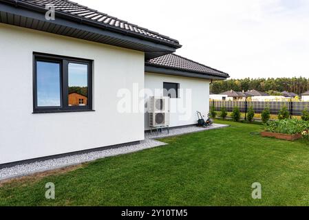 Two efficient outdoor heat pump units placed in front of the house. Stock Photo