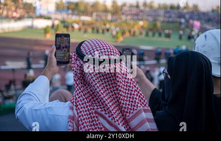 Arabic male and his wife taking video for graduation event for their son in the college field Stock Photo