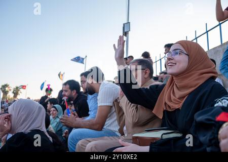 Arabic female watching her son graduation and waving for him while going to get his degree on stage Stock Photo