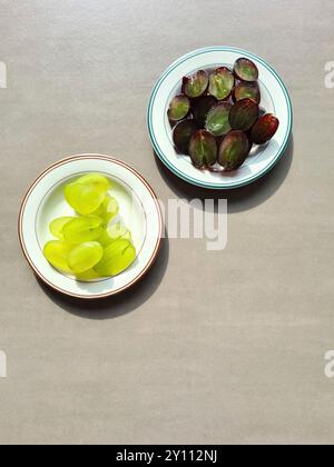 Fresh fruit on a white plate, vitamin-rich diet, healthy fresh light and dark sliced grapes arranged on two plates as a still life Stock Photo