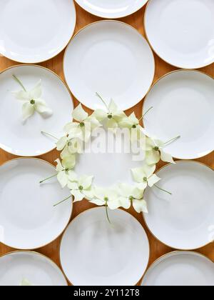 White plates with a gold rim are festively decorated with the flowers of the dogwood plant, preparation and decoration for a celebration, table decoration Stock Photo
