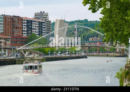 Bilboats tour boat Ibai Alai sailing down river towards the tied arch Zubizuri footbridge over the River Nerbiol Bilbao Basque Country Euskadi Spain Stock Photo