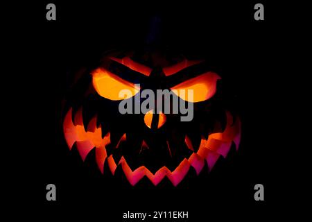 A pumpkin with a scary face on it. The pumpkin is orange and black. The face is angry and has a scary expression Stock Photo