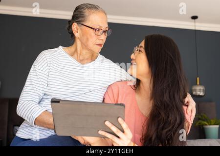 Using tablet,  asian grandmother and granddaughter bonding and smiling at home Stock Photo