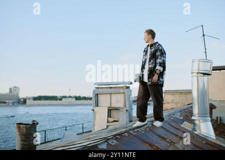 Contemplating Young Man on Rooftop Near Waterfront Stock Photo