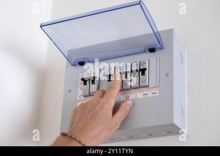 A man turns on a switch on an electrical panel in a room. Distributor Electricity. Stock Photo