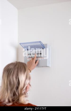 A man turns on a switch on an electrical panel in a room. Distributor Electricity. Stock Photo