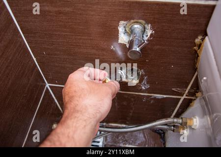 Close-up plumber tries to put stopper in pipe with water flowing Stock Photo